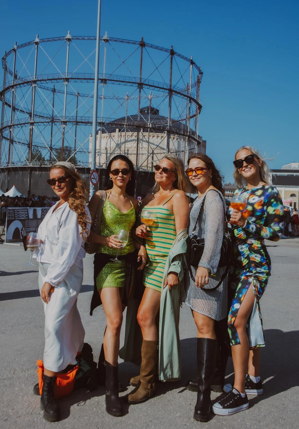 Группа девушек на фестивале в ярких нарядах под солнцем (Ryhmä naisia festivaalilla kirkkaissa asuissa auringossa).