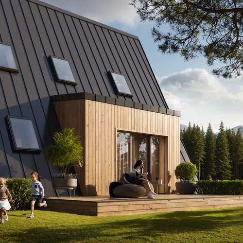A large, modern A-frame house with a dark metal roof and light wood siding features several skylights and a spacious wooden deck where children play on a sunny lawn overlooking a lake and mountains.