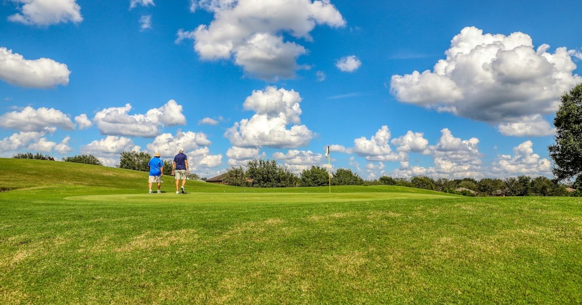 Golfers playing on a sunny green fairway at a golf facility