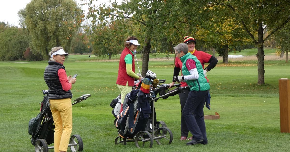 Two golfers walking the course together with bags on a sunny day