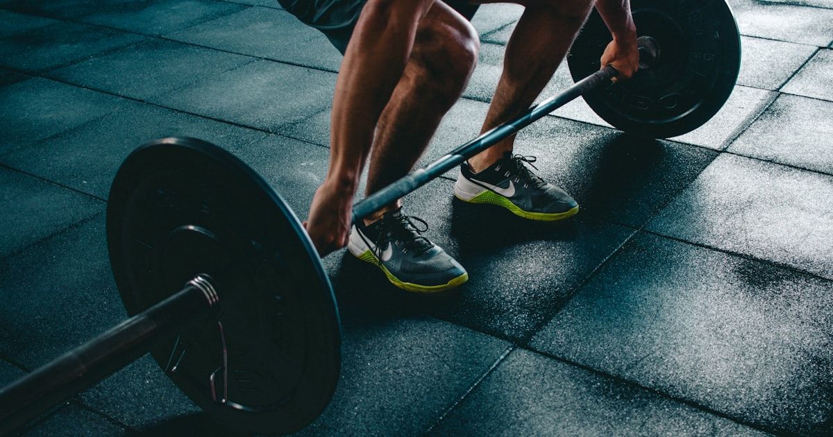 Person training with dumbbells in a well-equipped gym, representing accessible golf fitness training