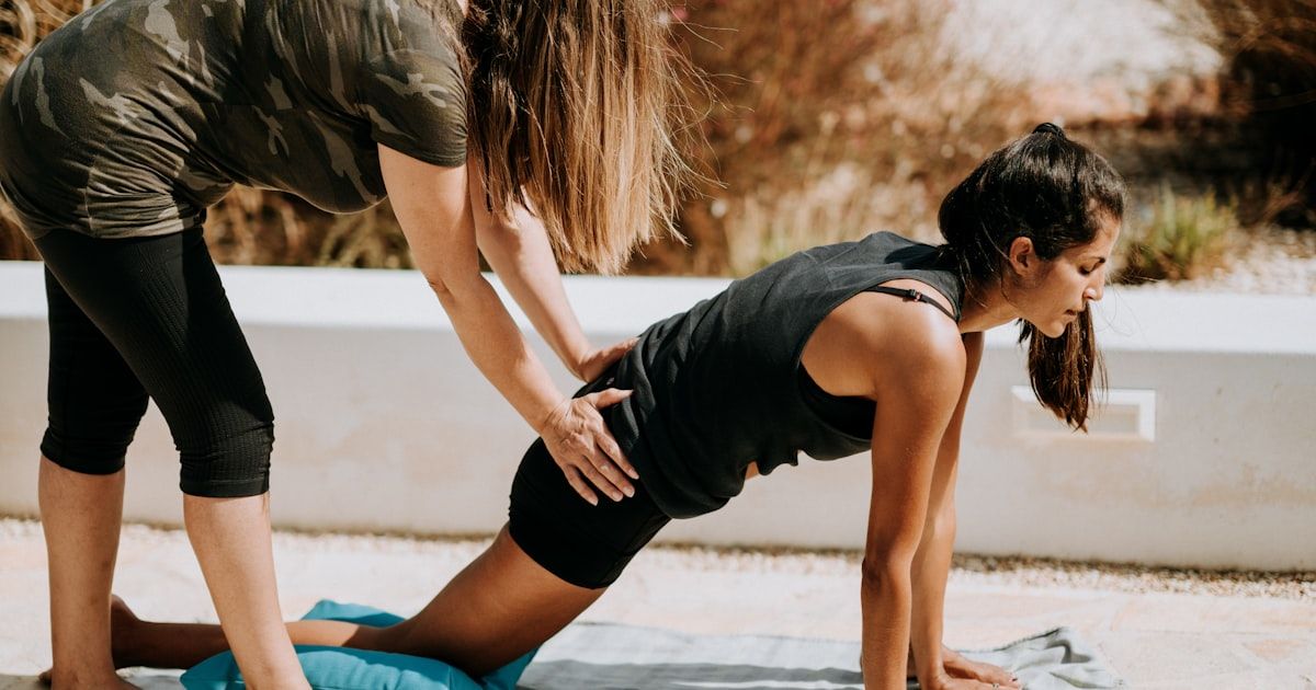 Fitness trainer coaching a client through an exercise on a mat