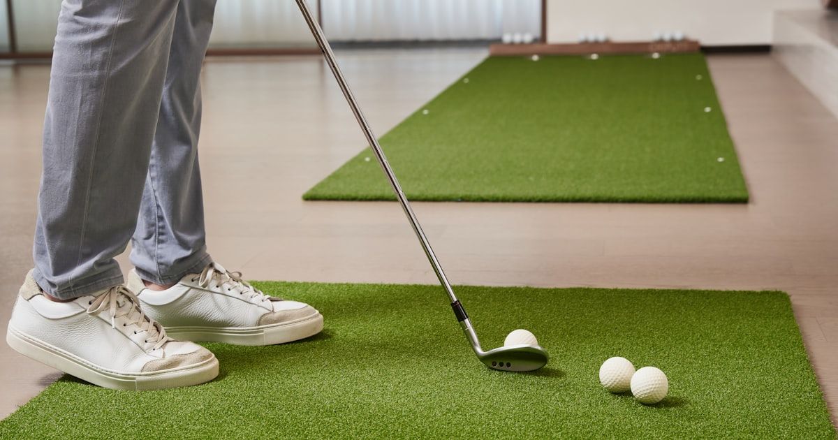 Collegiate golfer practicing swing mechanics on an indoor training mat