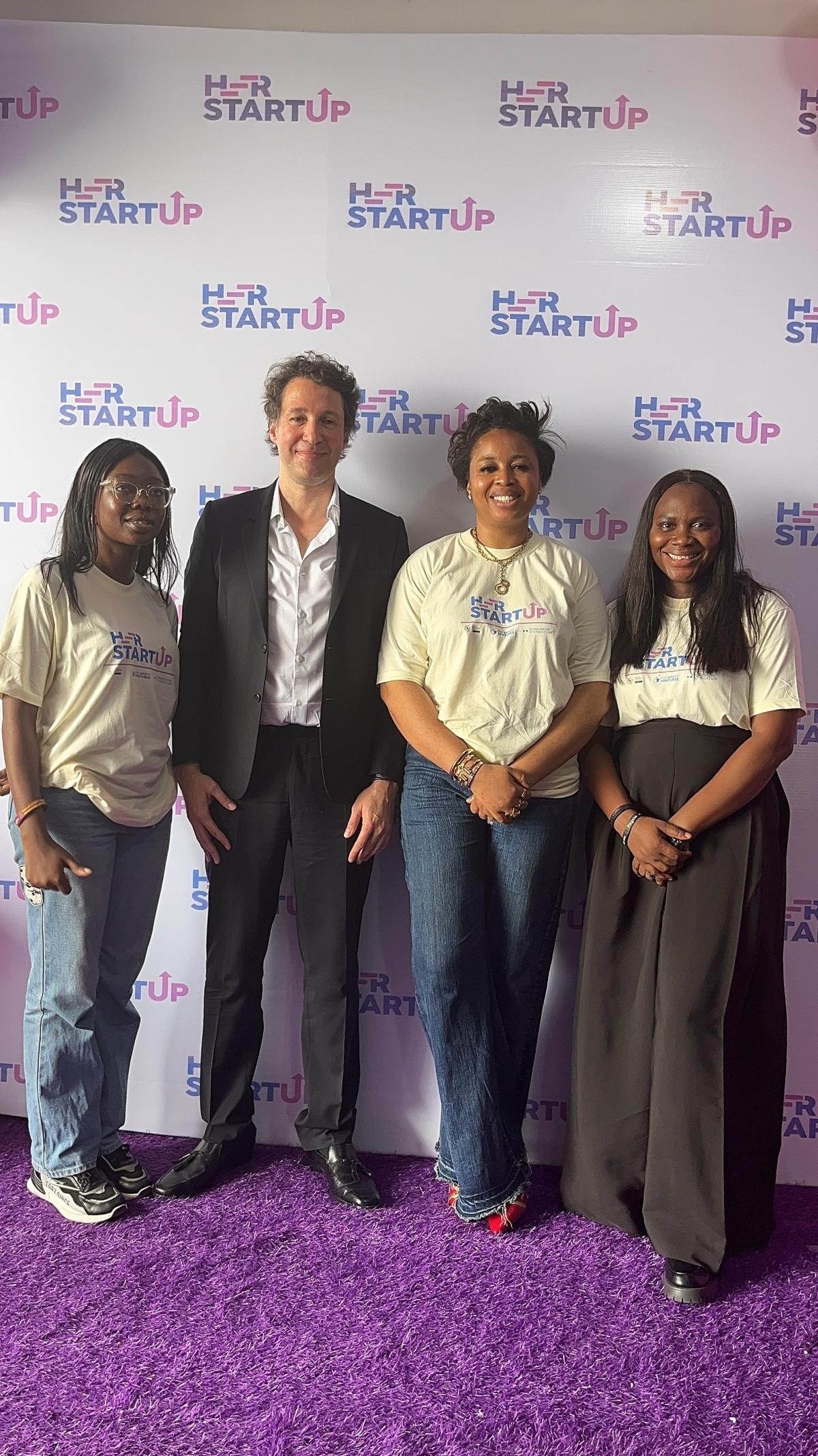 Women founders and program staff at a Her Startup event in front of a branded backdrop