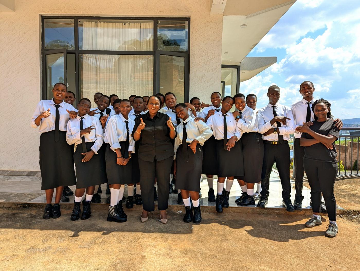 High-school students in white shirts and ties pose with a DIKAM host outside the factory offices
