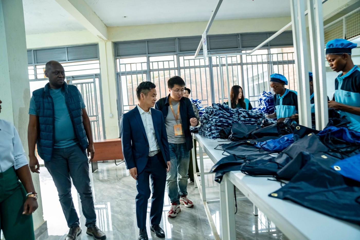 Sun Lijun of Alibaba tours the DIKAM production floor, where machinists in blue uniforms finish drawstring bags