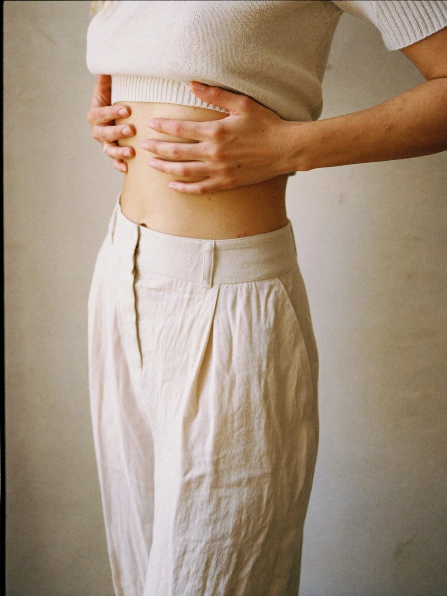 A woman resting her hands across her abdomen, where diastasis recti causes a central bulge