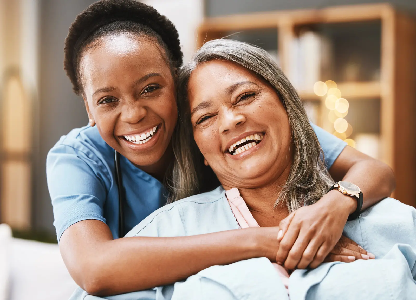 older woman smiling while being hung from behind by another happy young woman