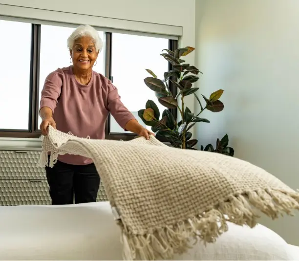 Woman feels at home, adjusts blankets.