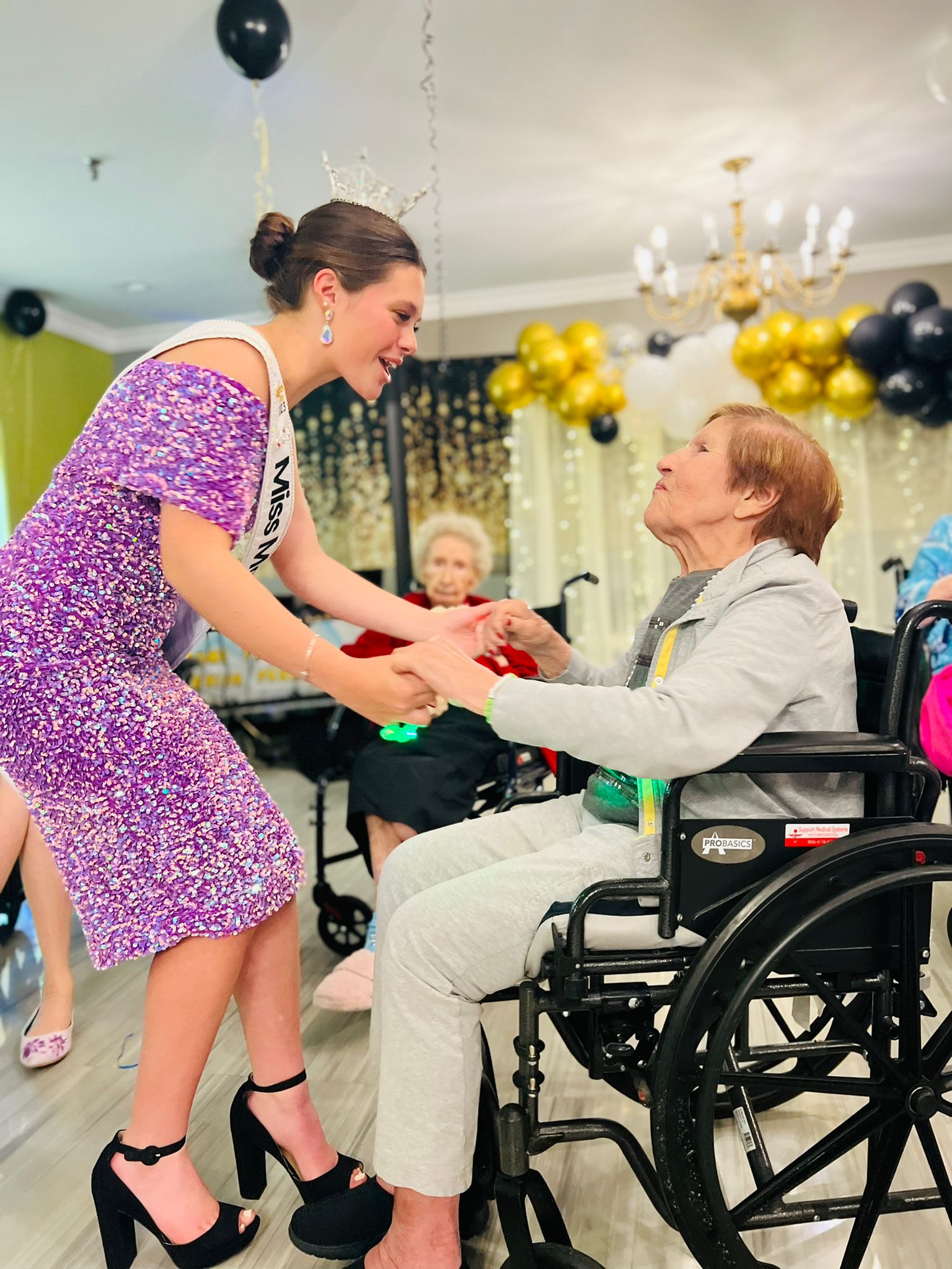 senior woman in wheelchair dancing with former beauty queen at senior living prom