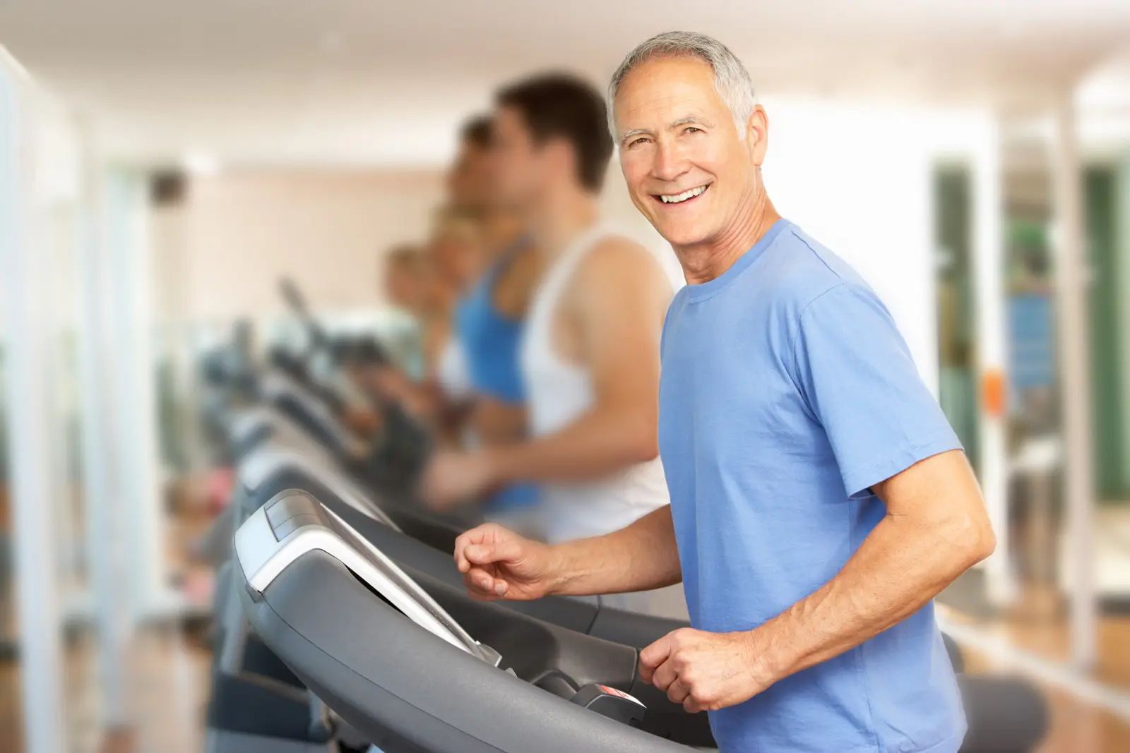 older man running on elliptical smiling as part of CardioPro rehab