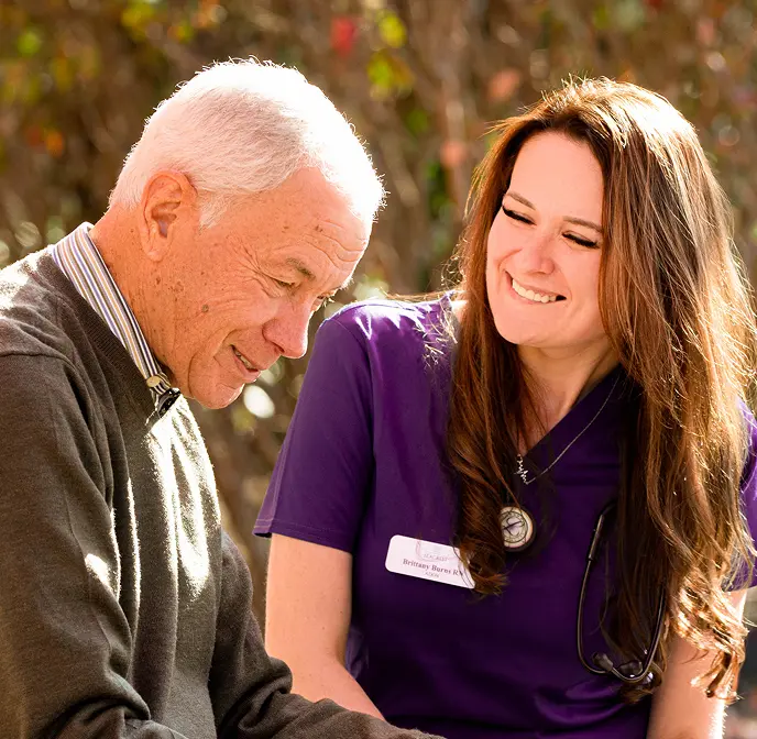 older man being comforted by young nurse in a park