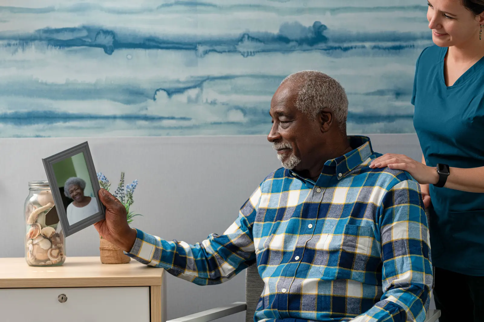 Older man smiling and looking at a framed picture of his lover