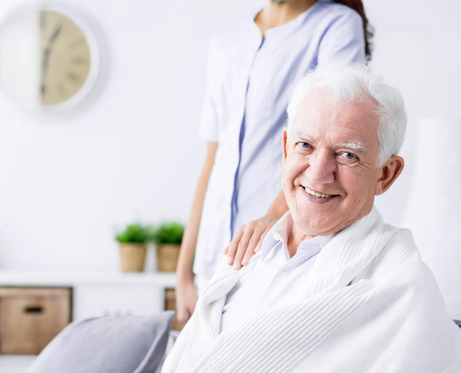 older man smiling wrapped in blanket while being comforted by nurse