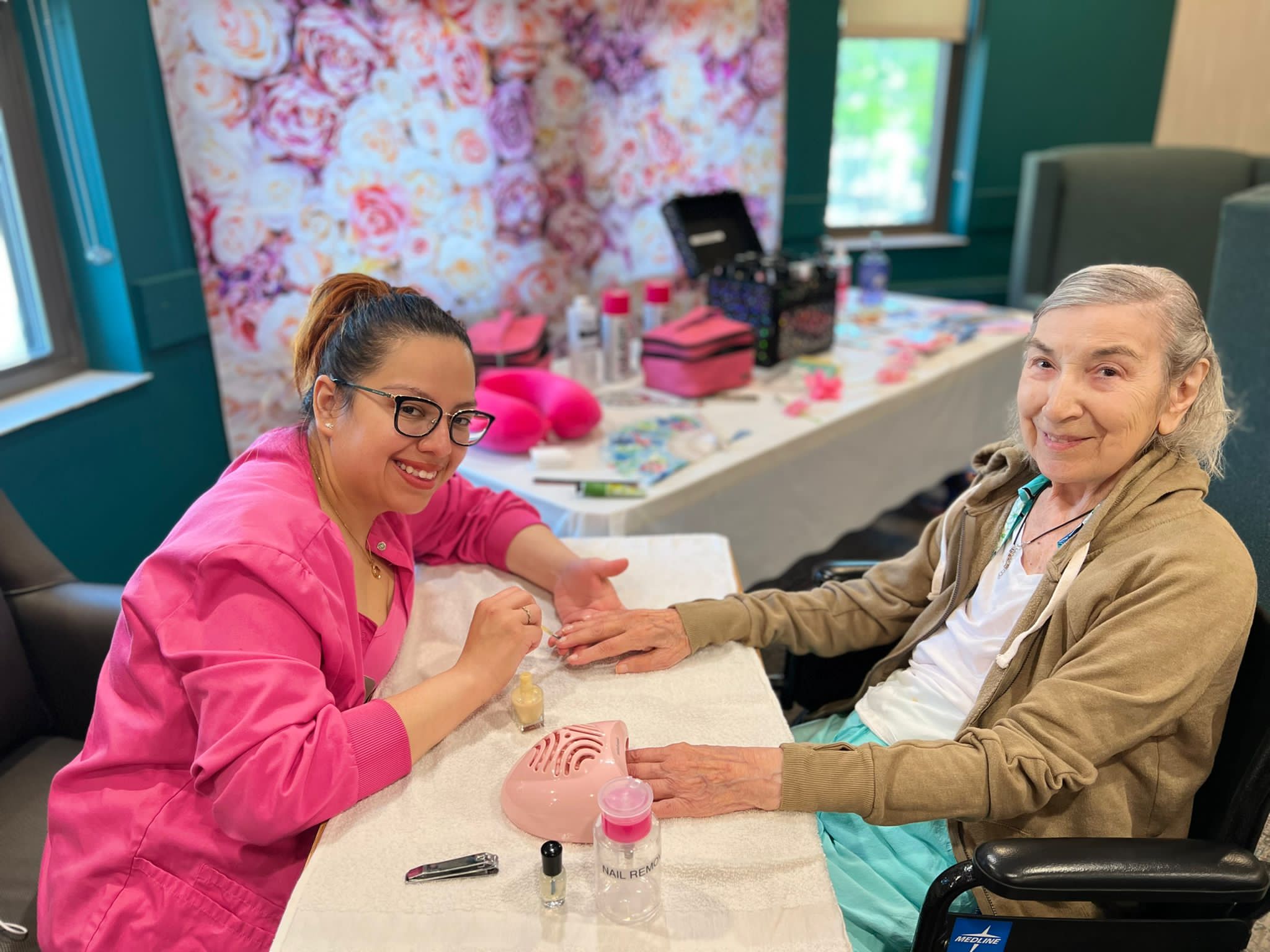older woman smiling while getting her nails done in a senior living setting