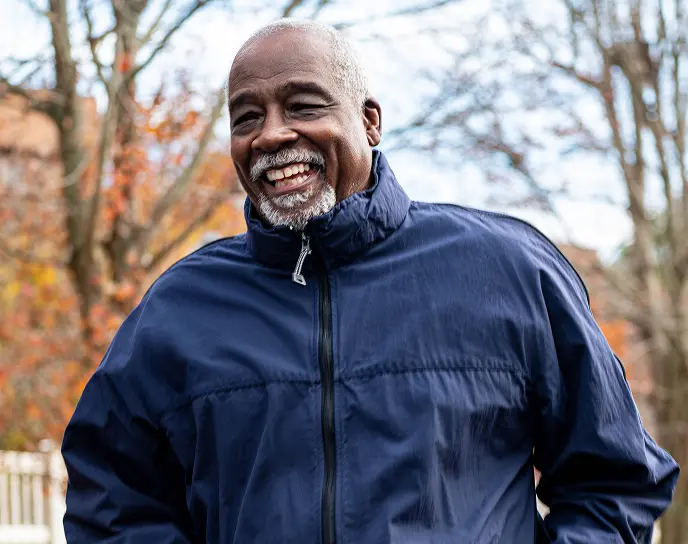 old man smiling and jogging outdoors