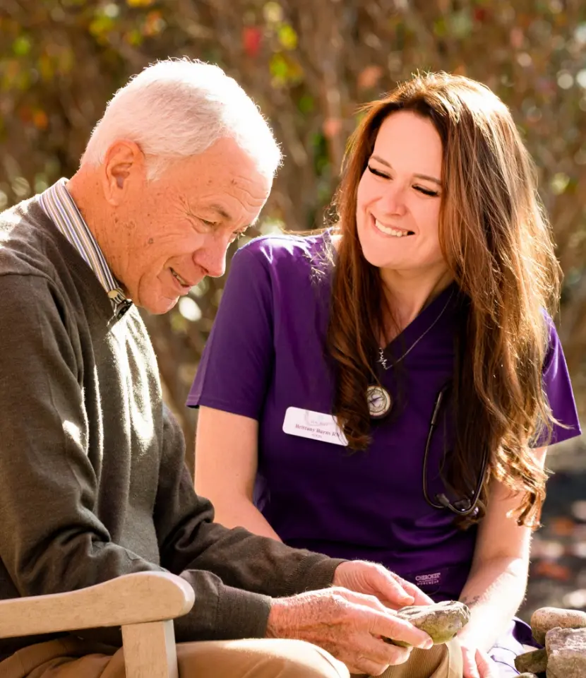 young nurse comforting older man on bench in park