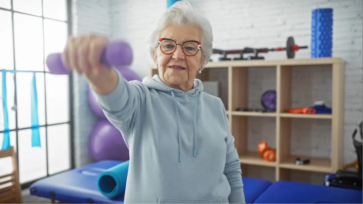 older lady lifting light weight as part of OrthoWin orthopedic rehab program