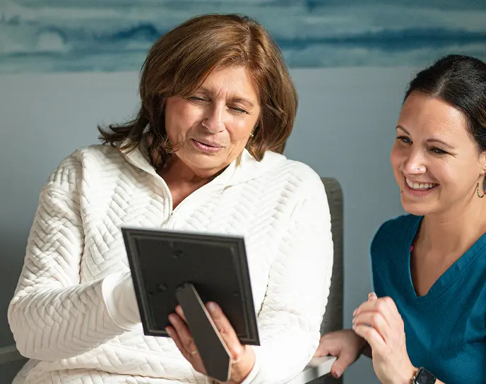 Smiling woman showing medical aide a framed picture