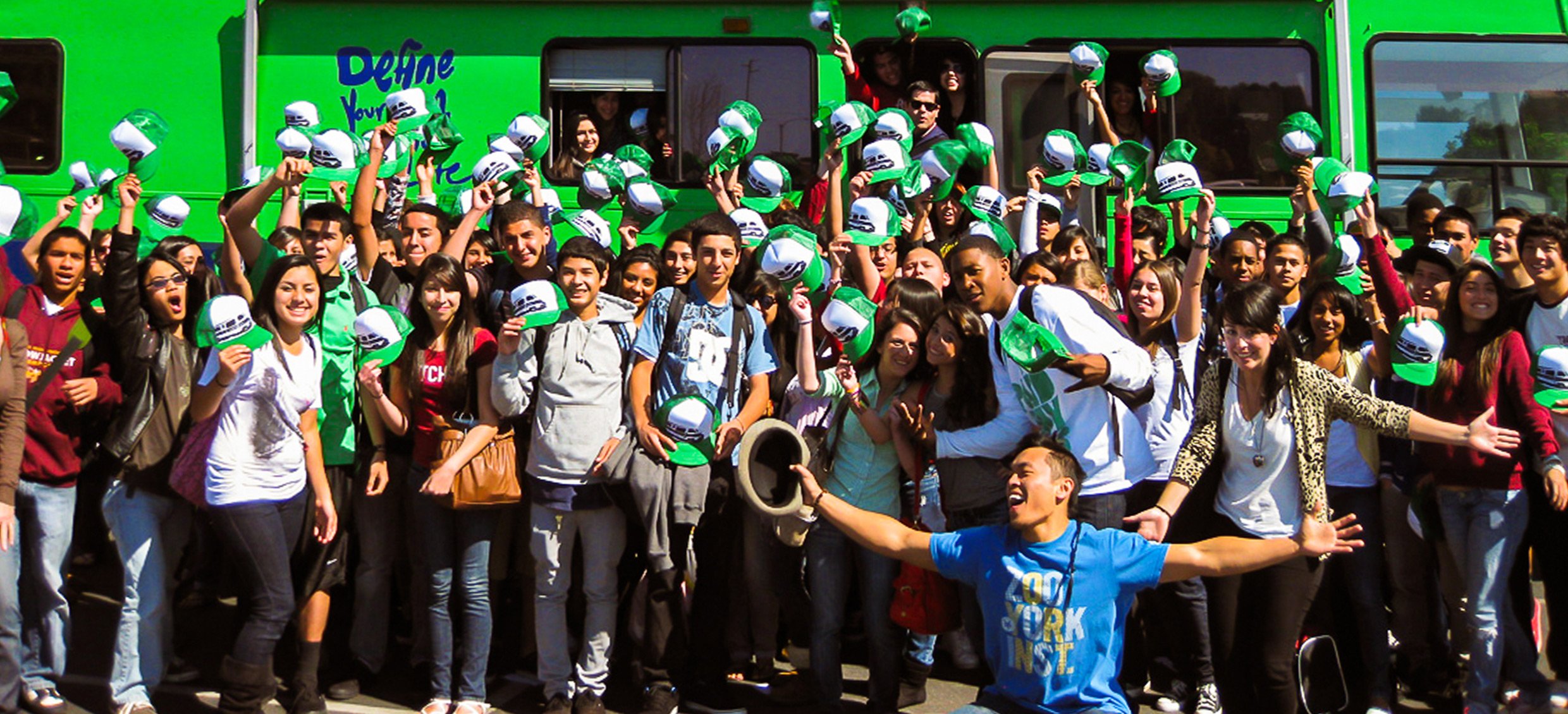 A group of students show off their Roadtrip Nation swag in front of the green RV