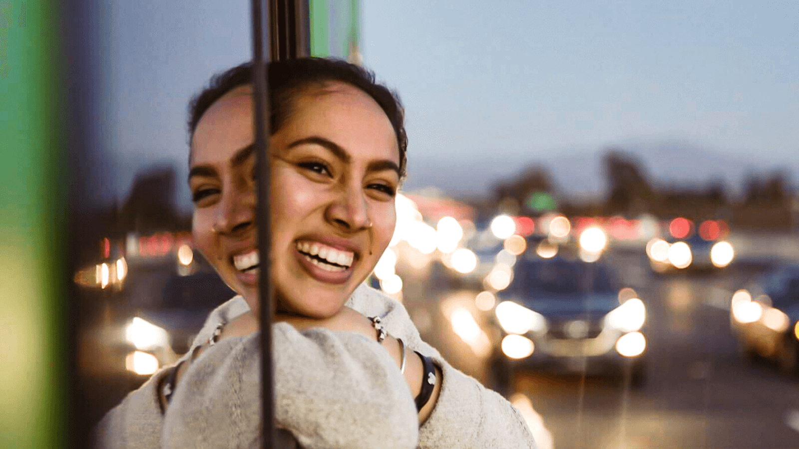 A smiling girl looks out the window of the Roadtrip Nation green RV.