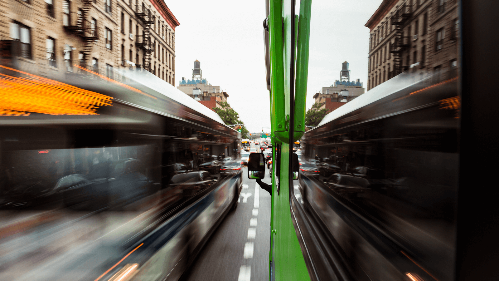 Cars rush by the Roadtrip Nation green RV as it drives down a busy city street.