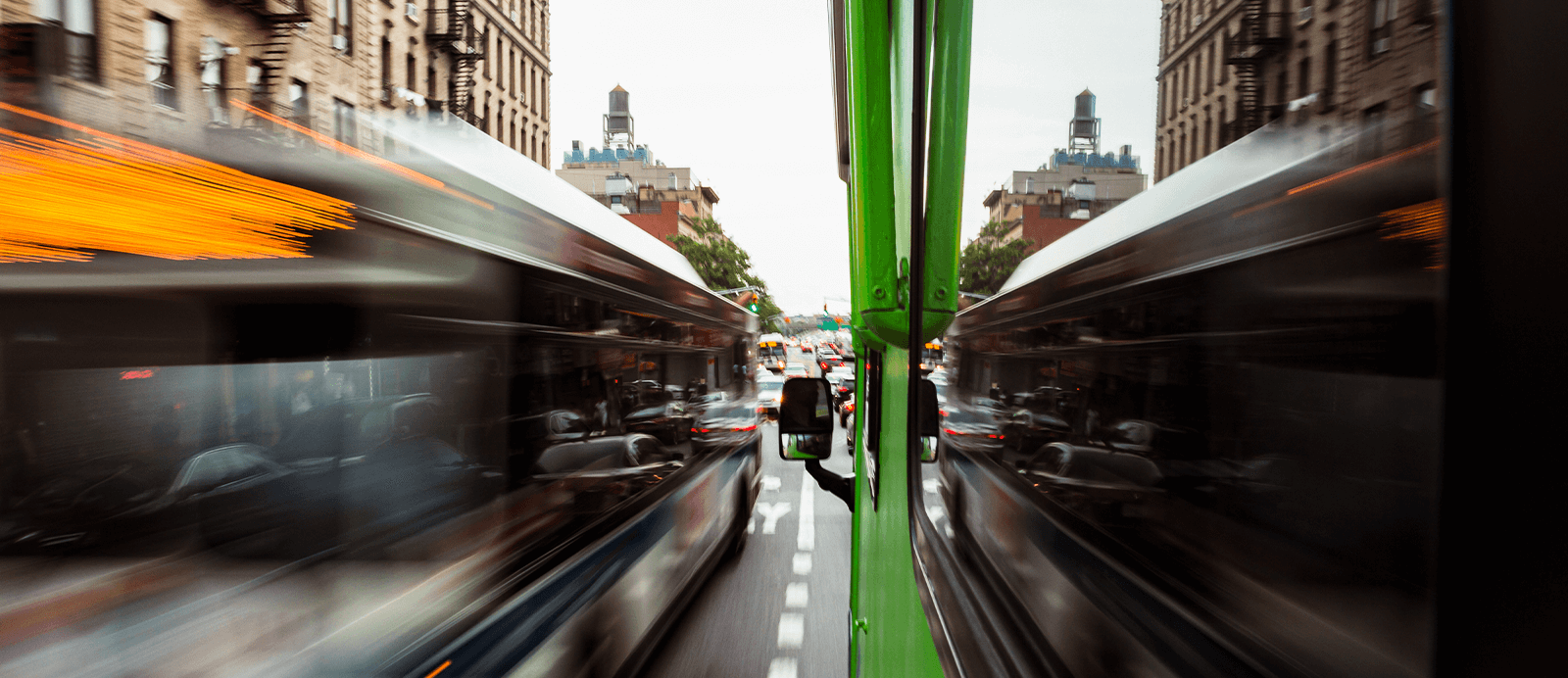 Cars rush by the Roadtrip Nation green RV as it drives down a busy city street.