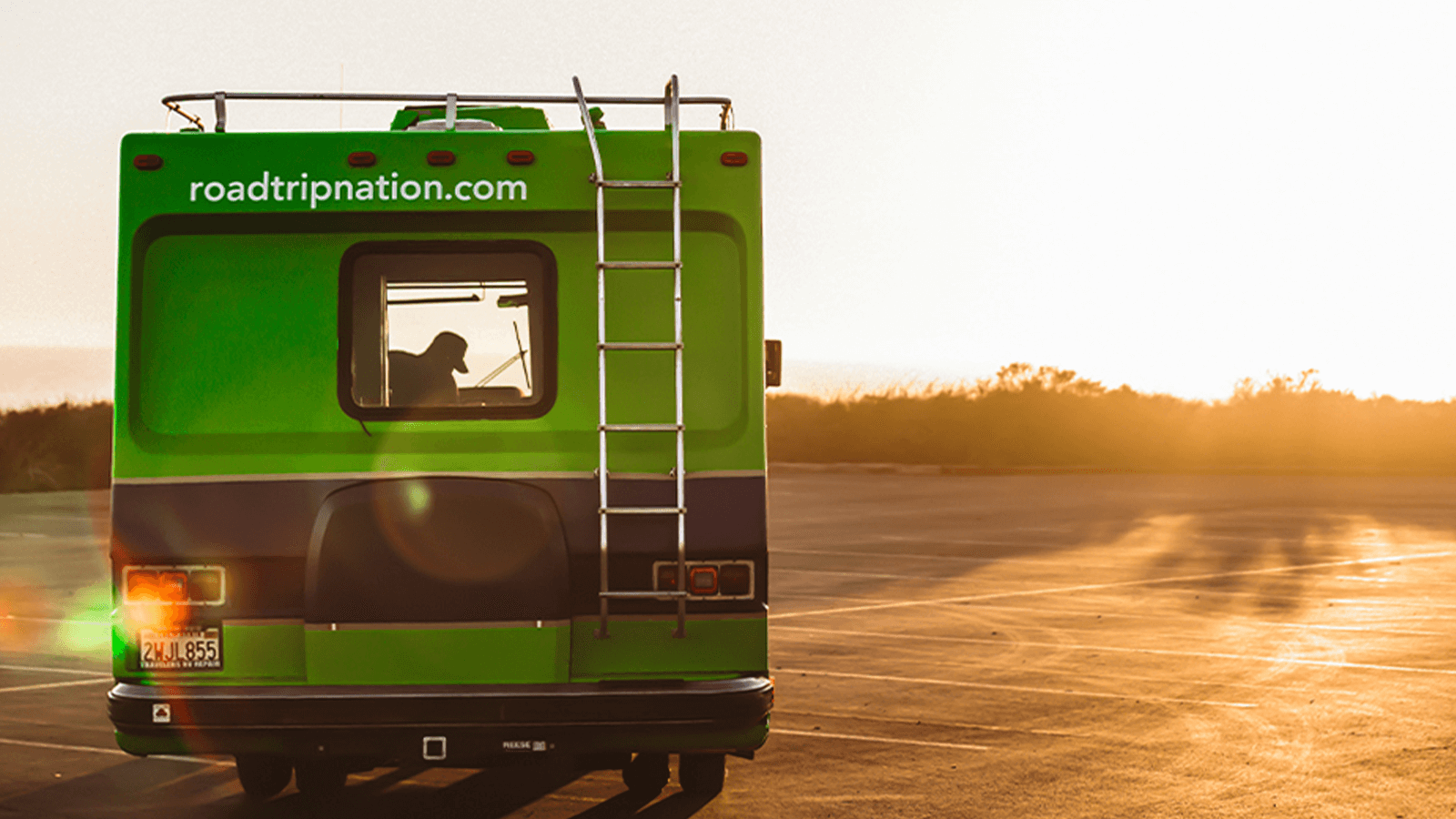 The sun sets in front of the Roadtrip Nation green RV.