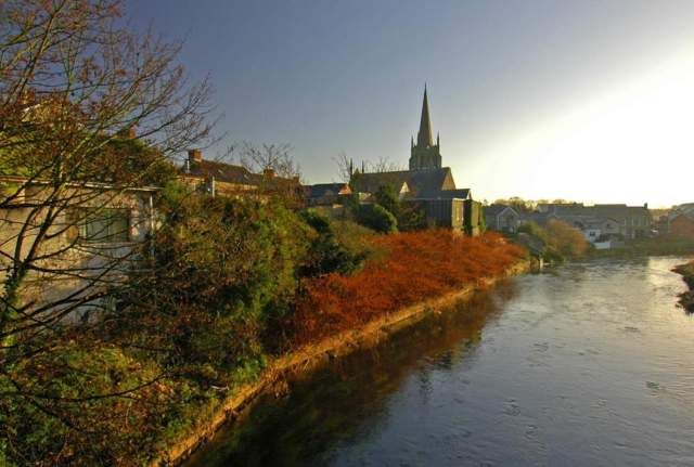 A church spire above the river in Antrim town, used as the header image for the Lowe Design web design in Antrim page