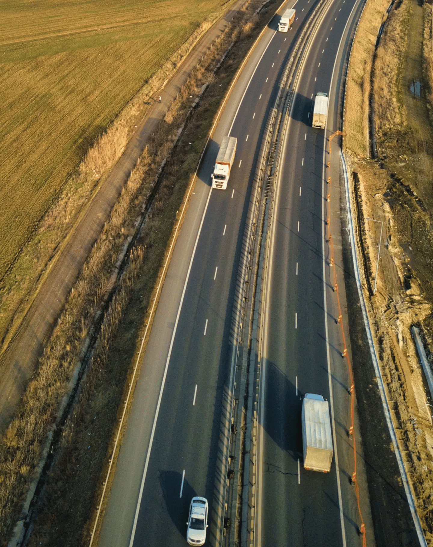 Two lane highway with cars and cargo trucks passing quickly on both sides. 