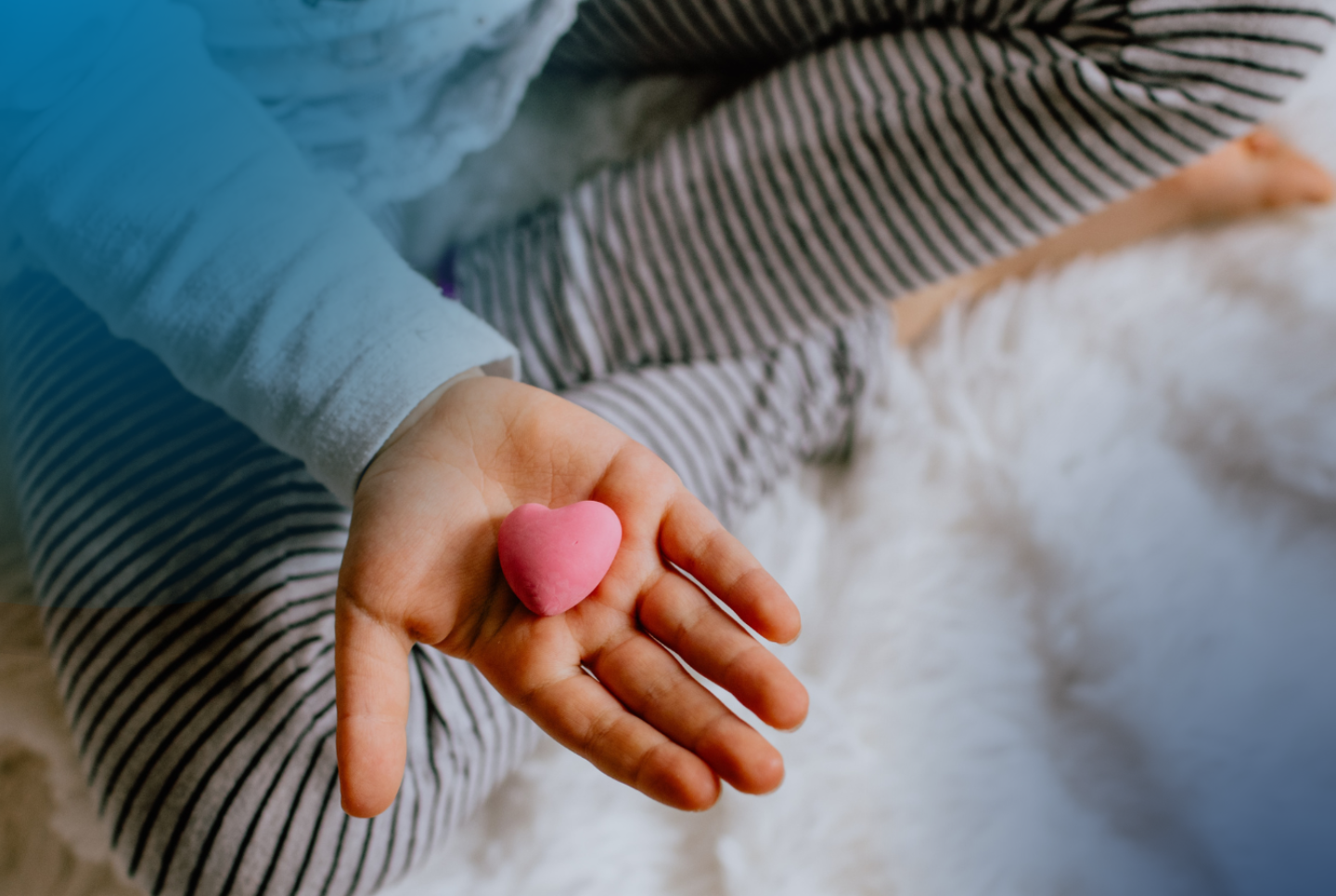 Child's hand holding a pink heart, For new parents, navigating time-off as their family grows is stressful, especially considering most Americans do not have access to paid family leave through their employer. 