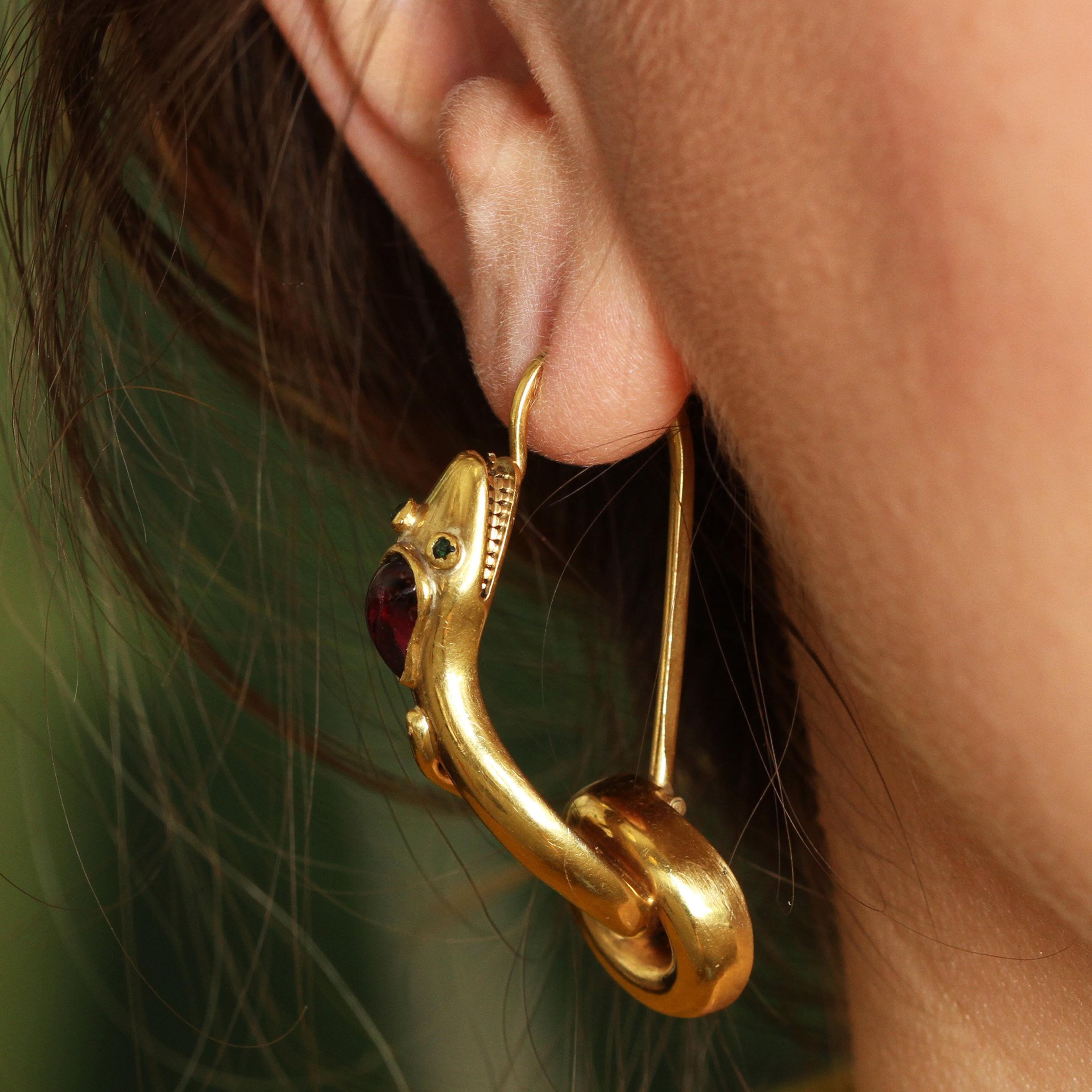 Closeup of Serpent Earrings with Garnet Cabochons and Emerald Eyes worn in a pierced ear