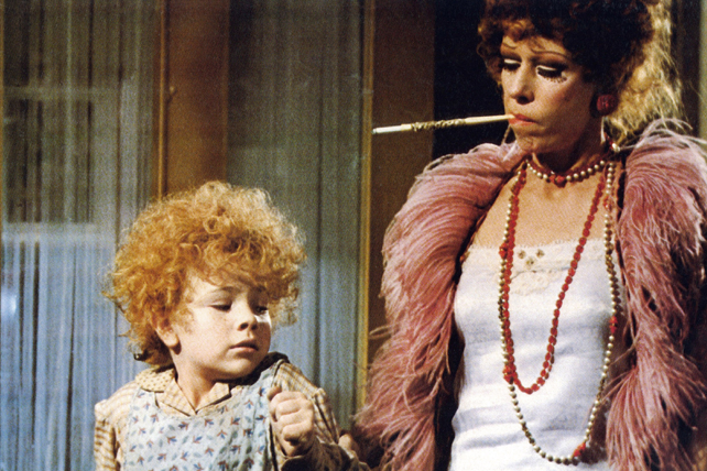 A photo still from the 1982 movie Annie of Miss Hannigan holding young Annie's arm.