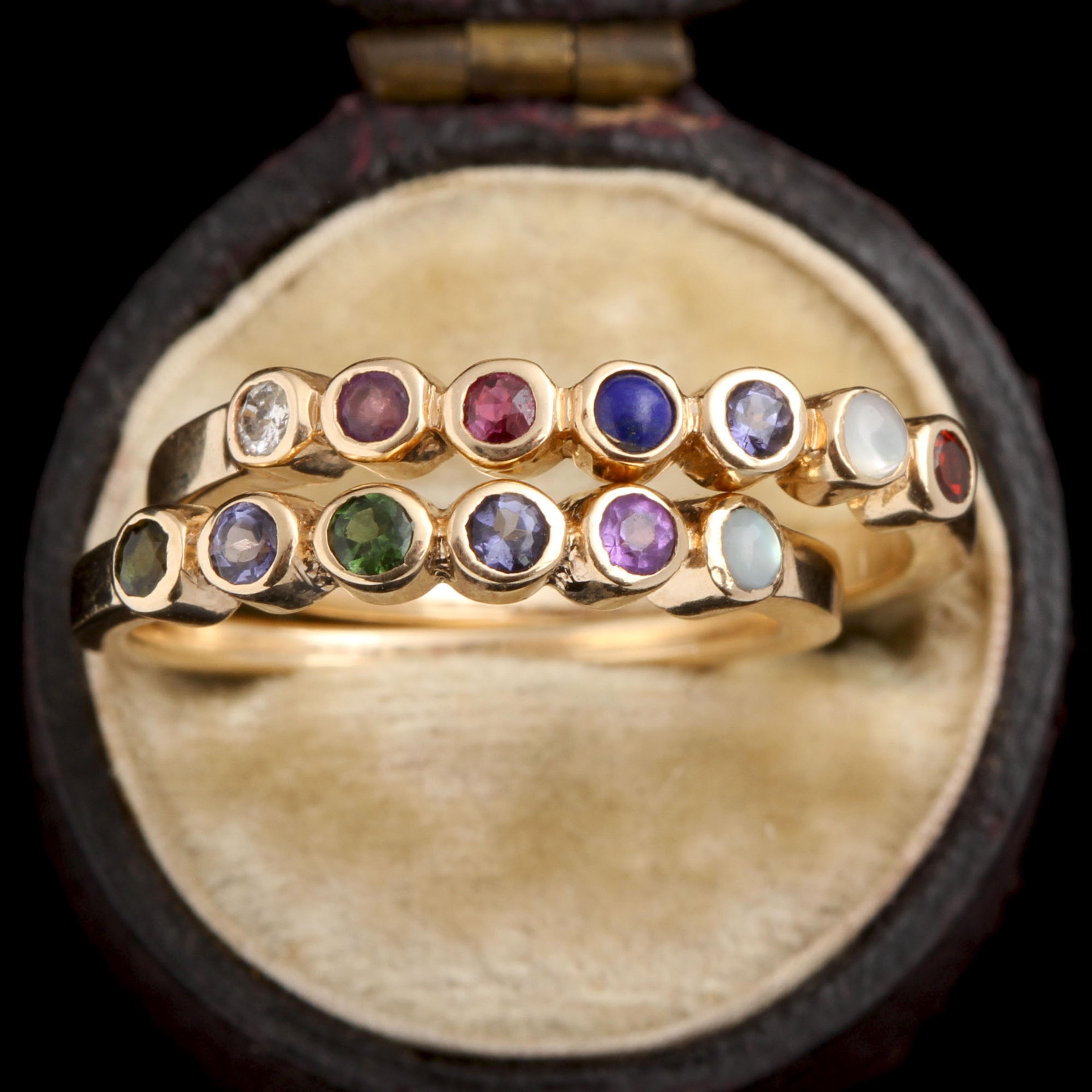 Detail of two yellow gold acrostic rings spelling Darling and Vivian