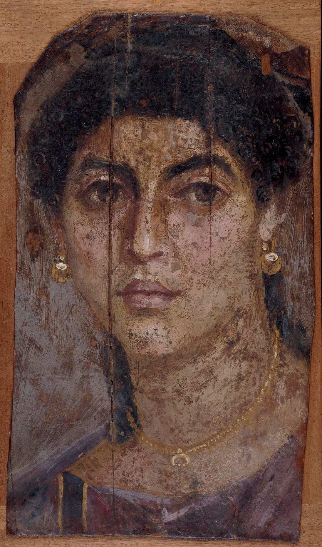 A mummy portrait from Roman-Egypt depicting a woman wearing a lunula pendant, 55-70 AD. Part of a collection of mummy portraits known as the Fayum Portraits. The British Museum.