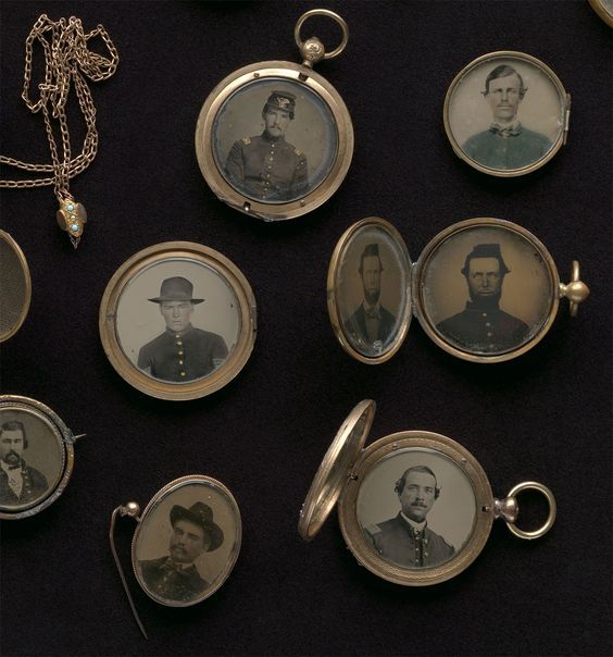 A photograph of an assortment of lockets from the 1800s, all open to reveal tintype photographs of Civil War soldiers inside.