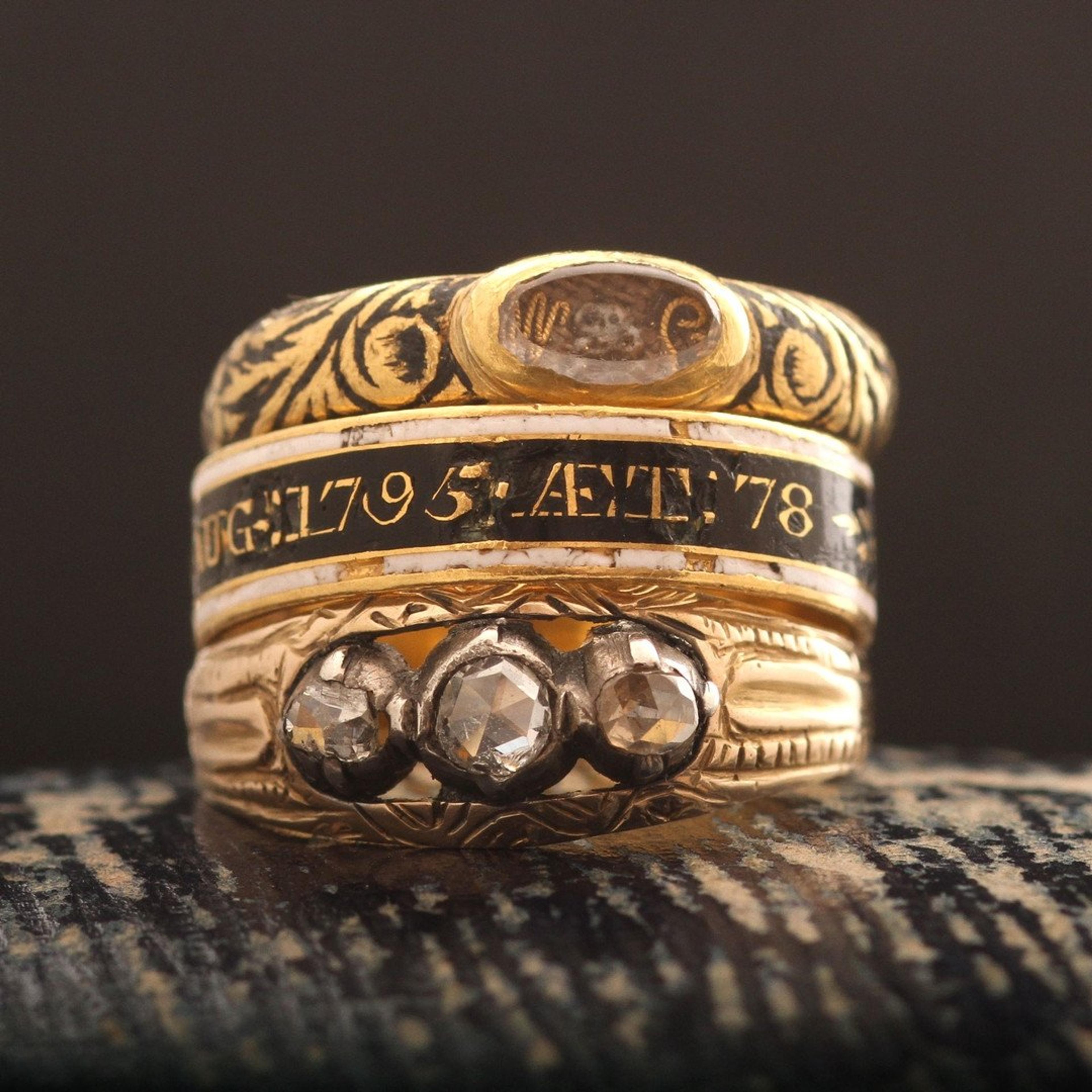 A stack of rings including the Baroque Mourning Ring with Skull and Crossbones and Cipher