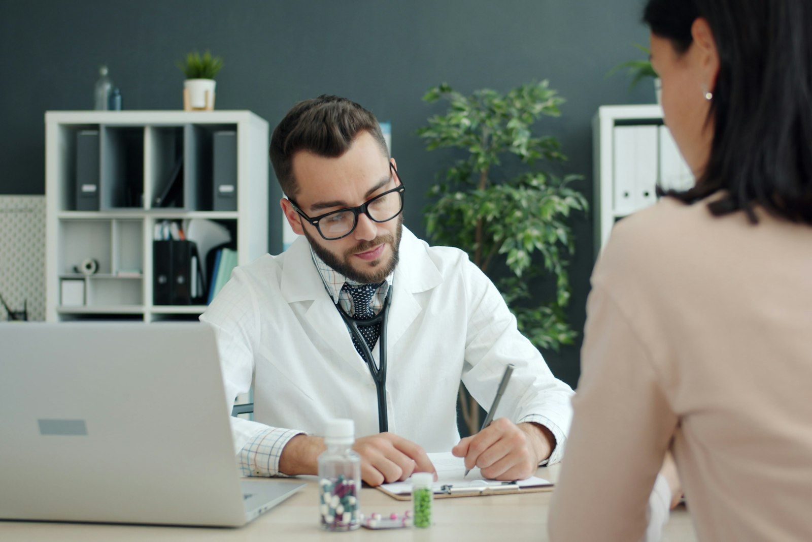 A clinician making notes while talking with a patient