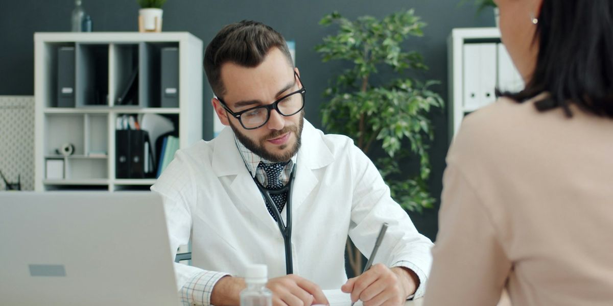 A clinician making notes while talking with a patient