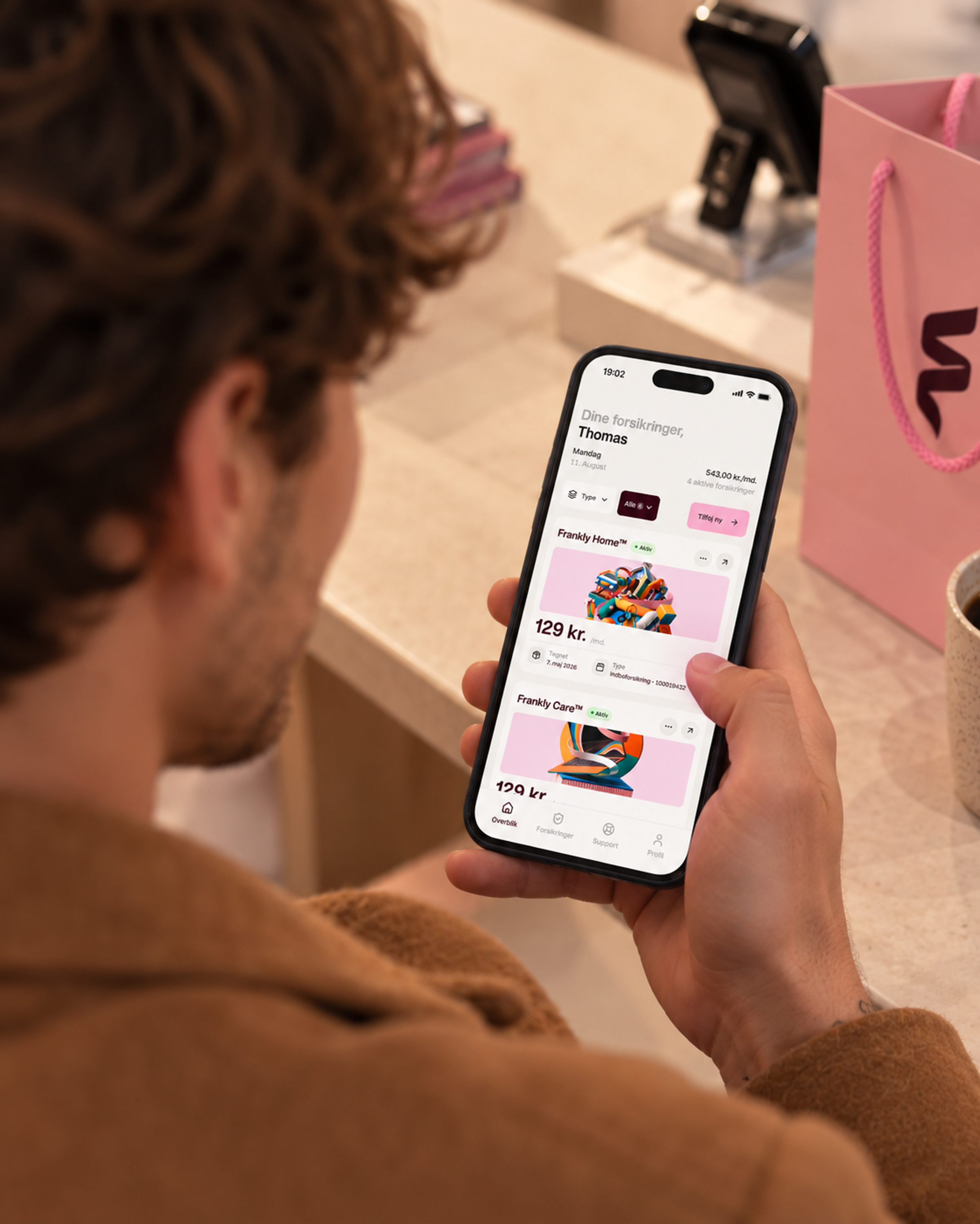Mand ser sine forsikringer i Frankly-appen i butikken