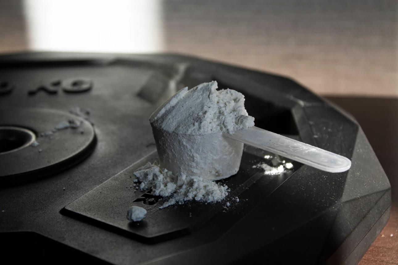 overflowing scoop of creatine monohydrate sitting on top of plate weight