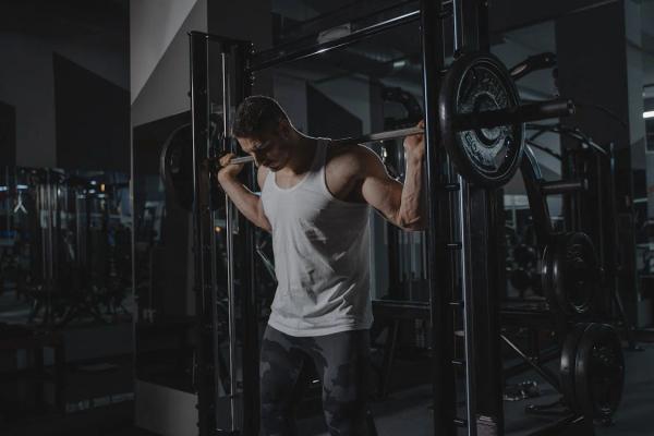 man performing high bar back squats using smith machine