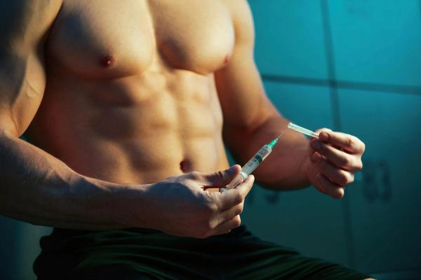 Close up of shirtless sportsman holding injection 
