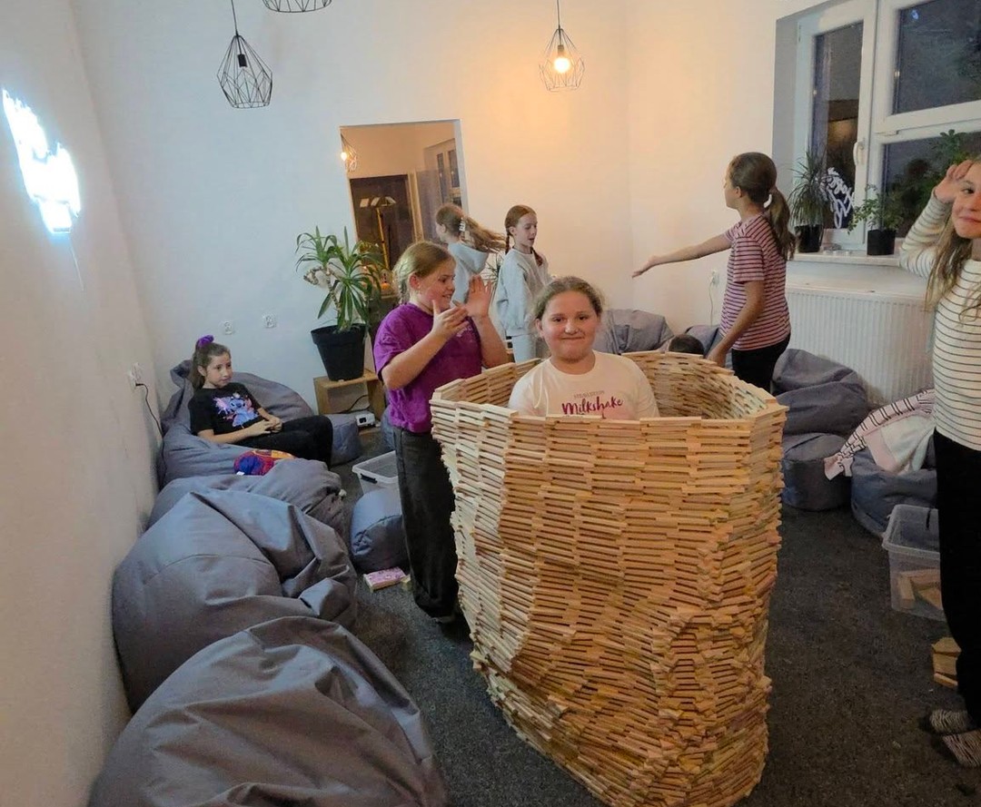 Dzieci bawią się pod kolorową chustą na łące