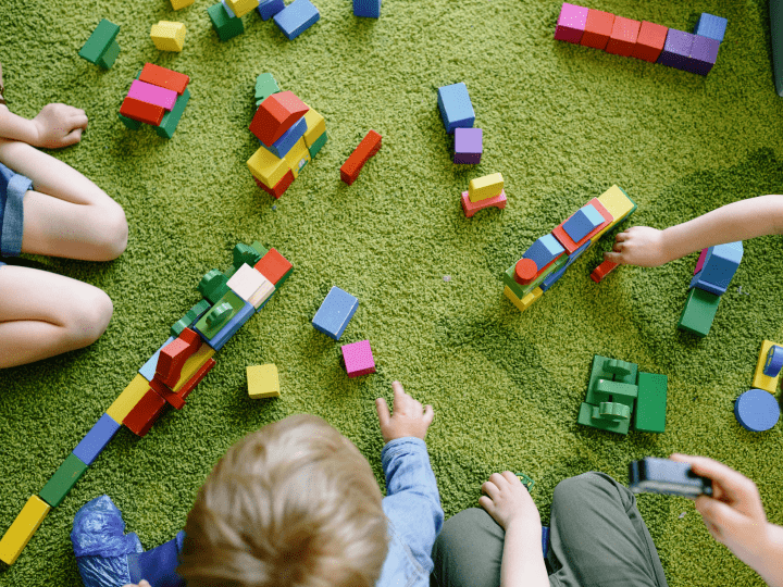 Dzieci bawią się klockami na zielonej macie