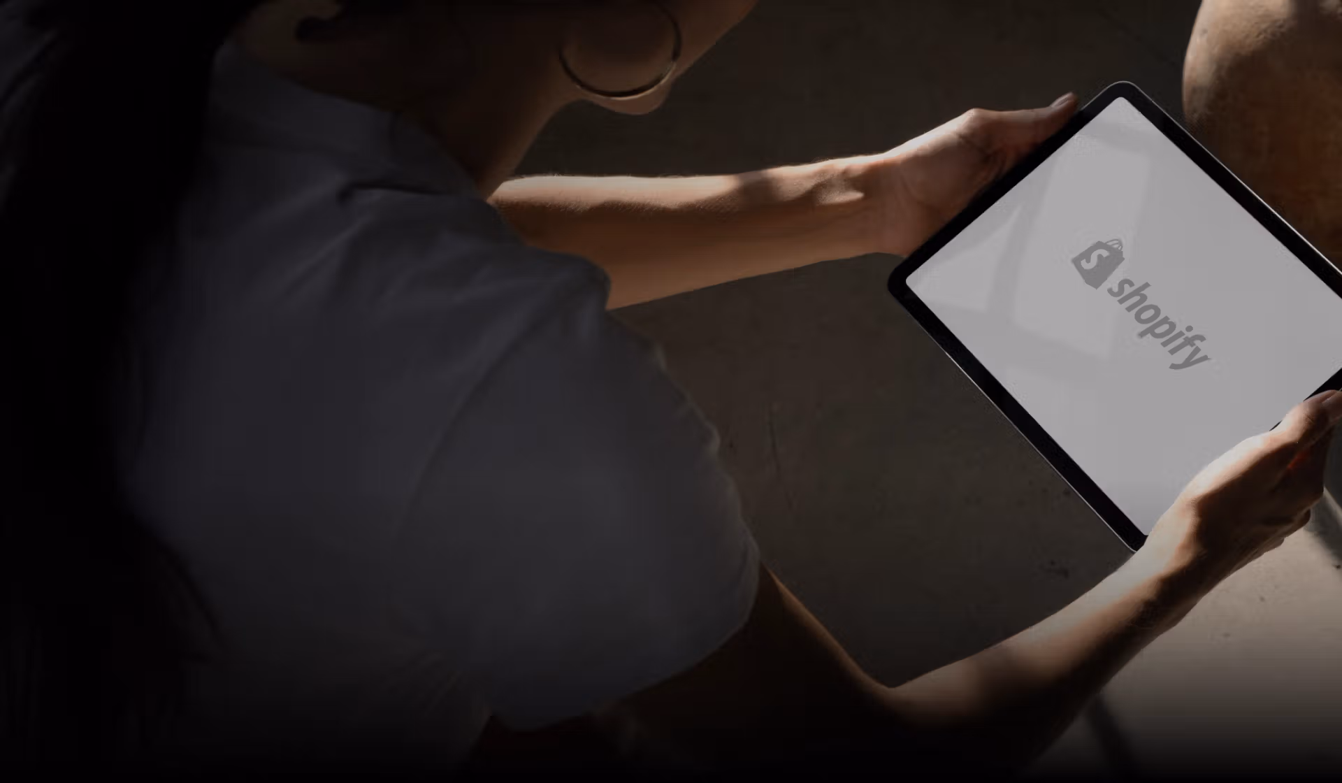 A person holding a tablet showcasing a Shopify logo