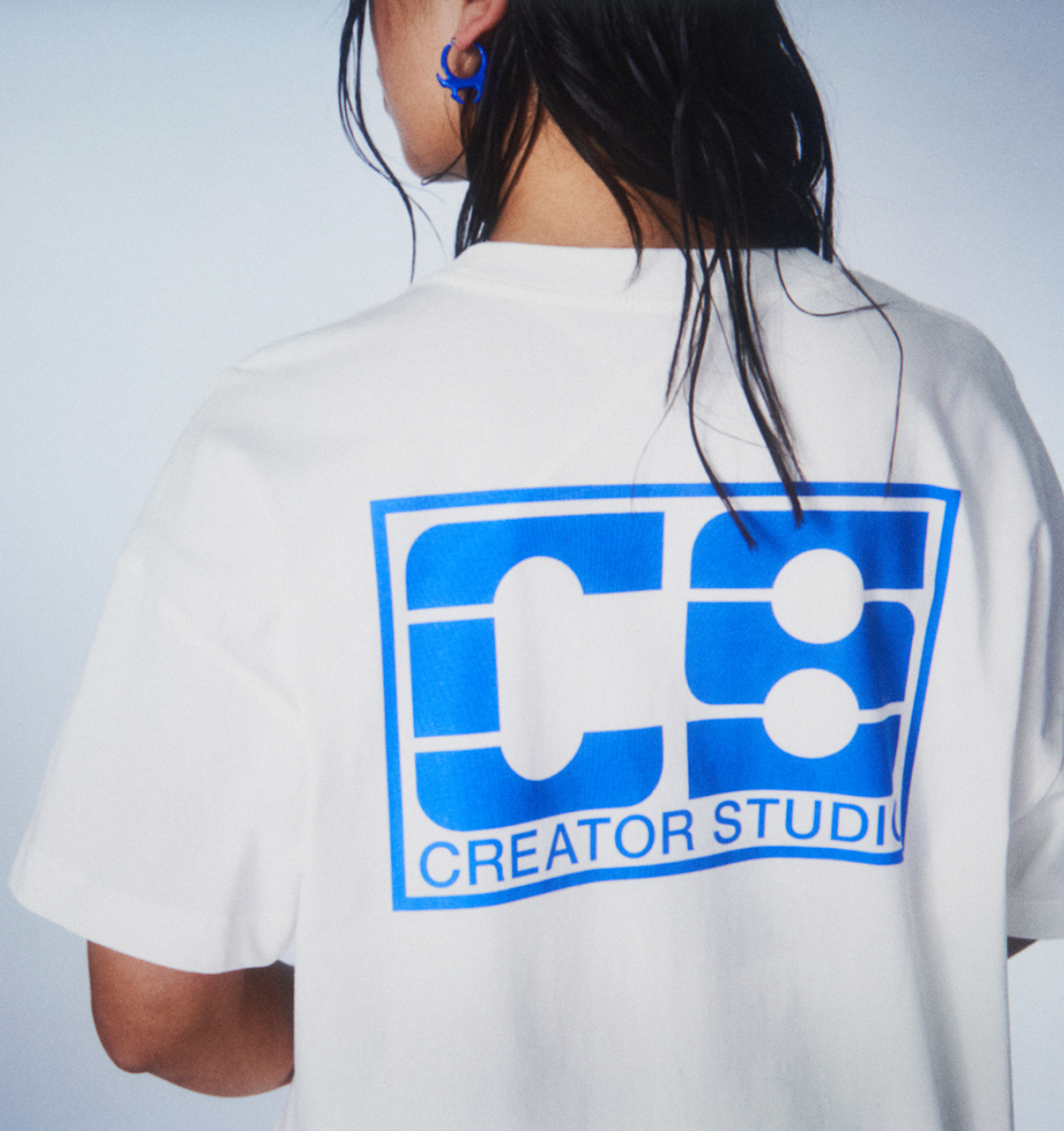A model wearing a white custom t-shirt with Creator Studio print