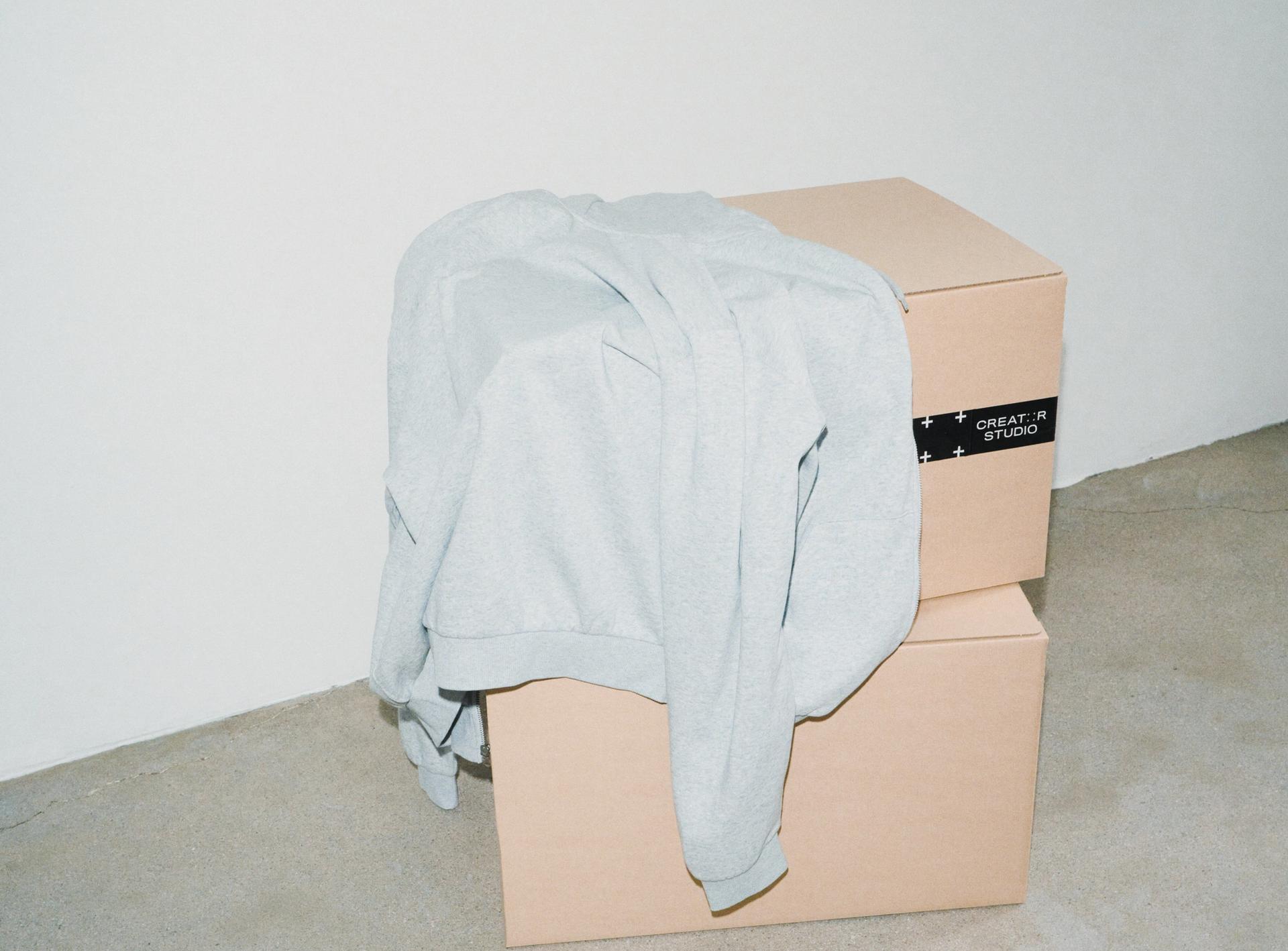 A Creator Studio zip hoodie laid on two stacked packaging boxes
