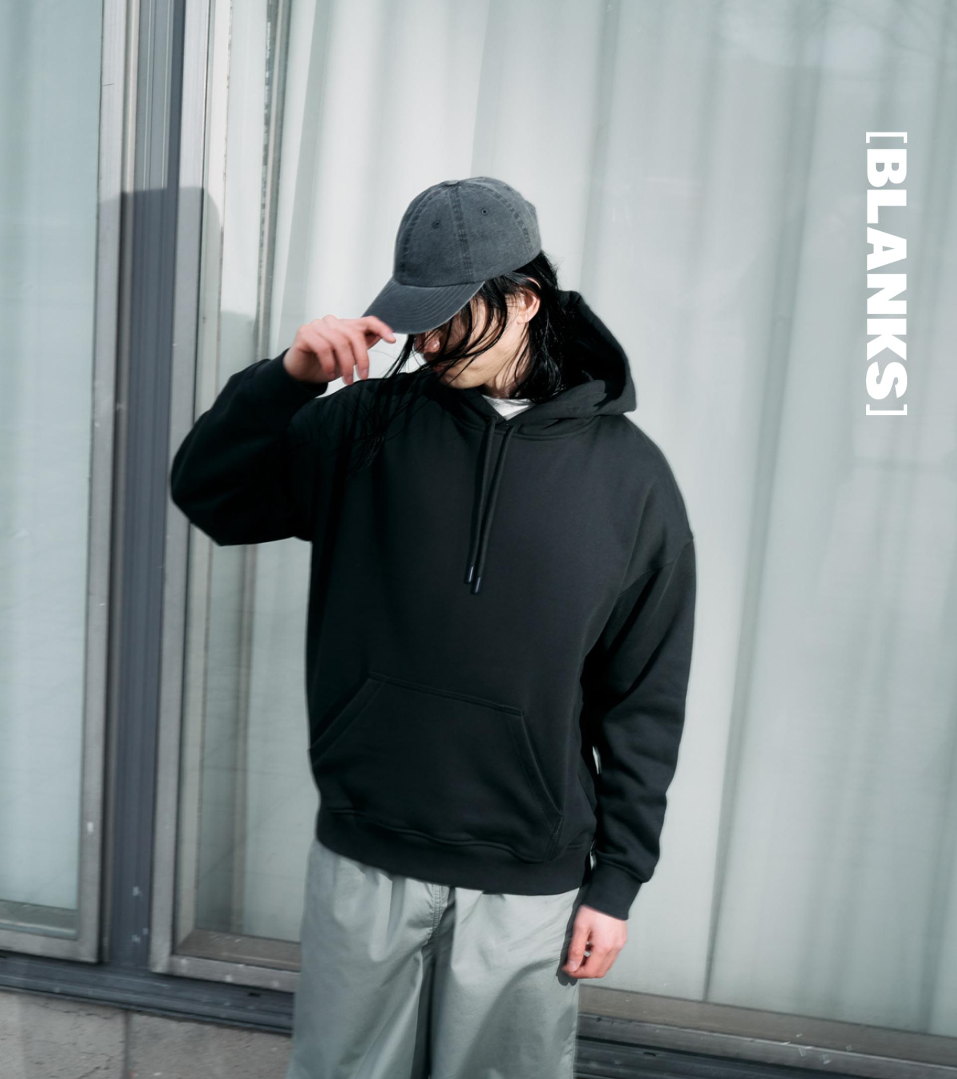 A model wearing a black hoodie and grey cap in the city