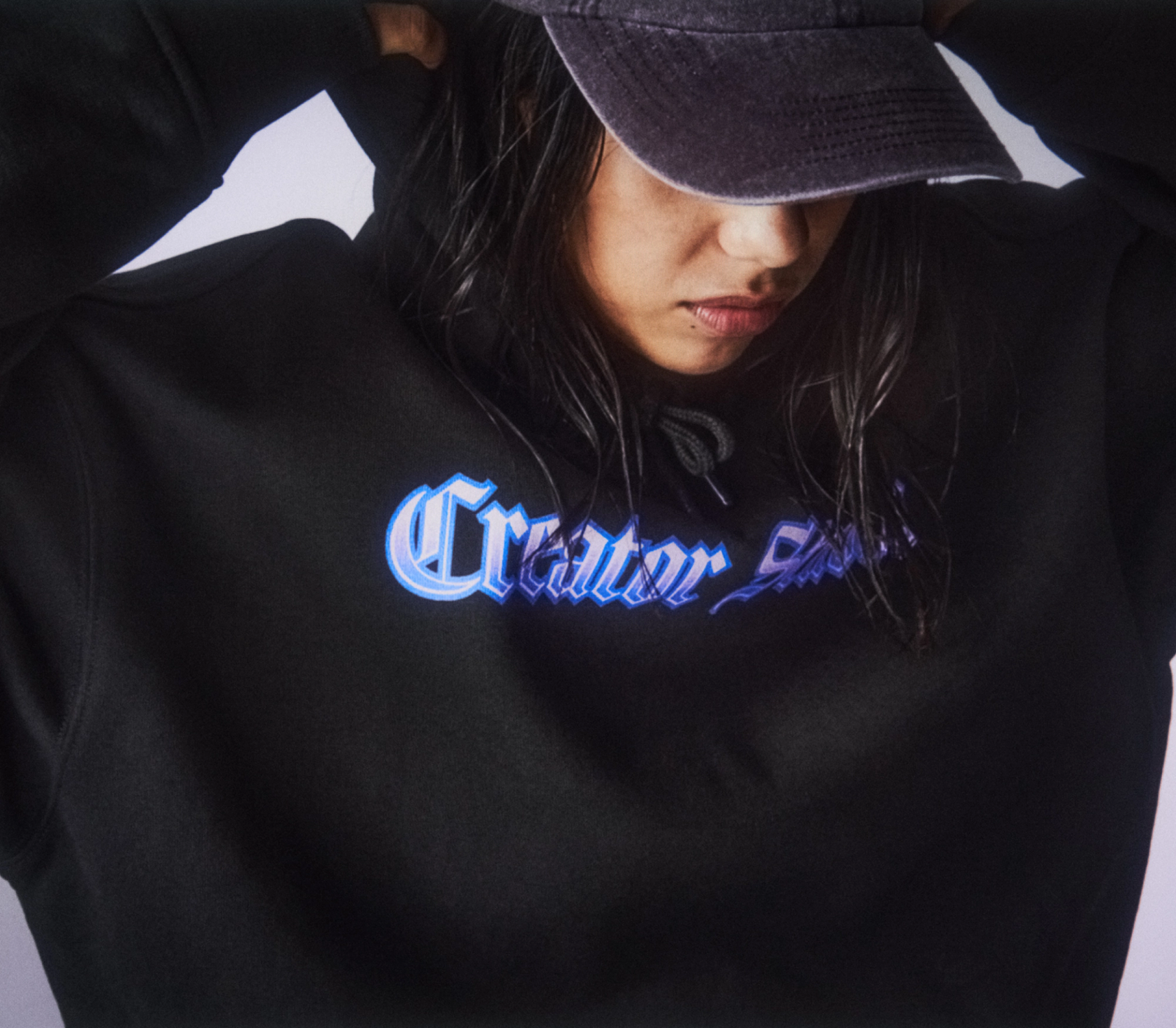 A model wearing a black hoodie with Creator Studio print
